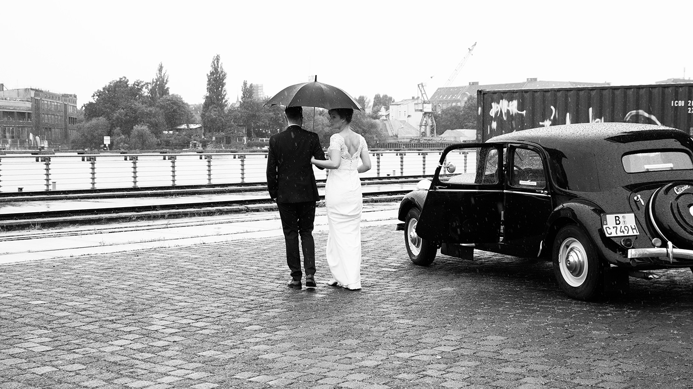 Ehepaar im Regen neben Oldtimer
