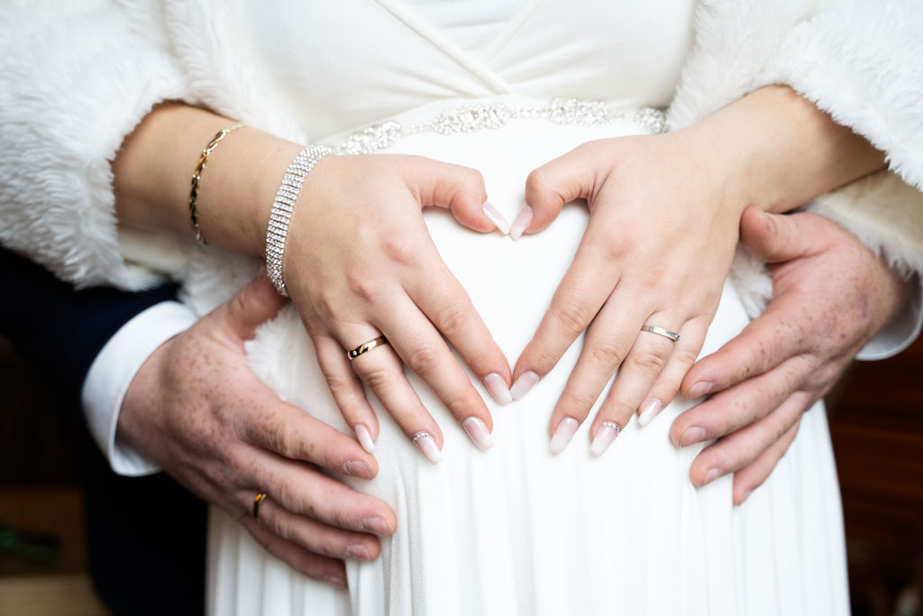 Schwangere Braut mit Ihrem Ehemann hält Babybauch